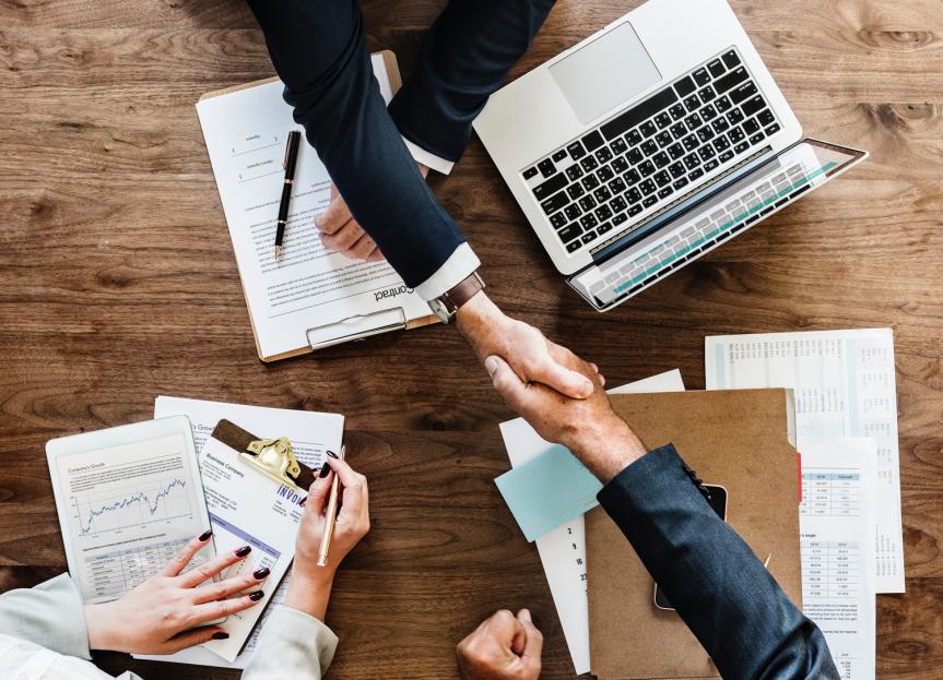 Three People Shaking Hands in a Meeting Across the Table 