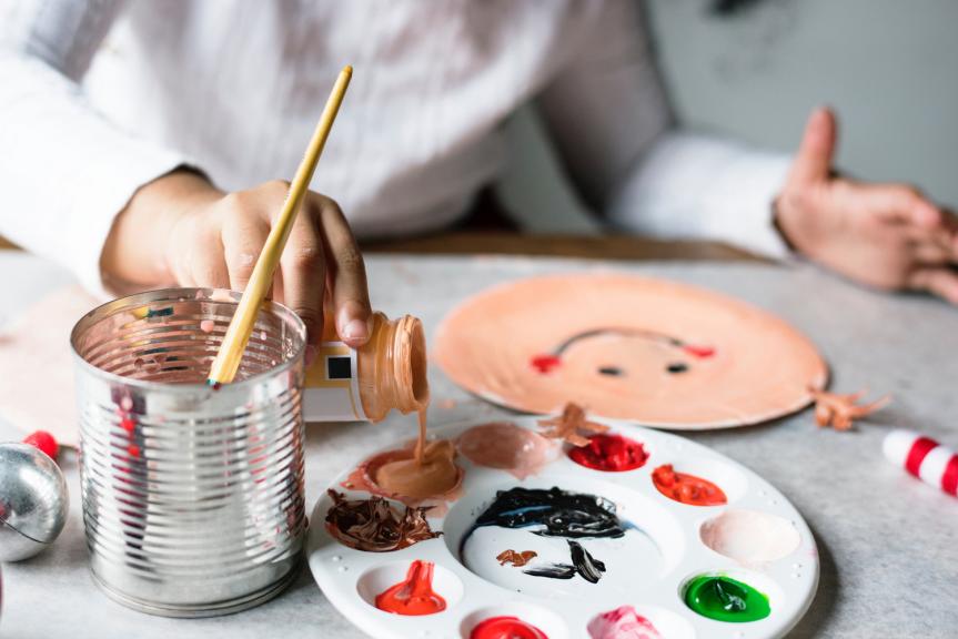 Woman Sitting at Table Painting Plate with Smiley Face