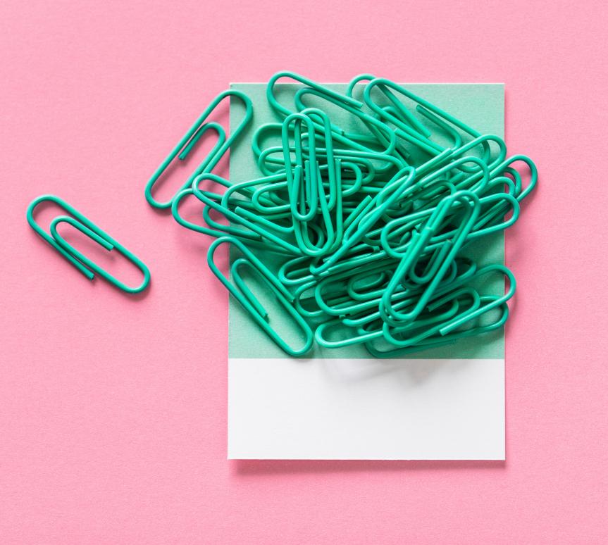 A pile of Green Paperclips on a Pink Background