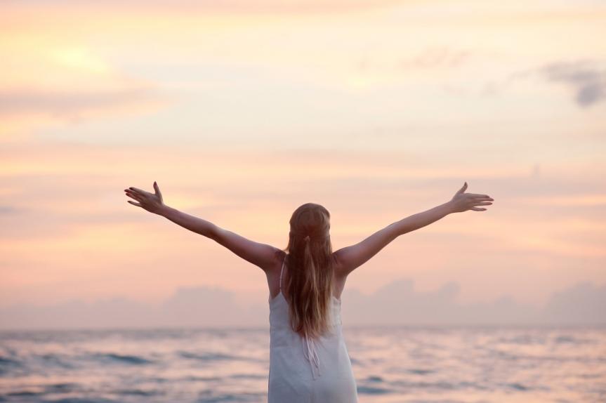 Girl with Arms Spread out and a Sunset Background 